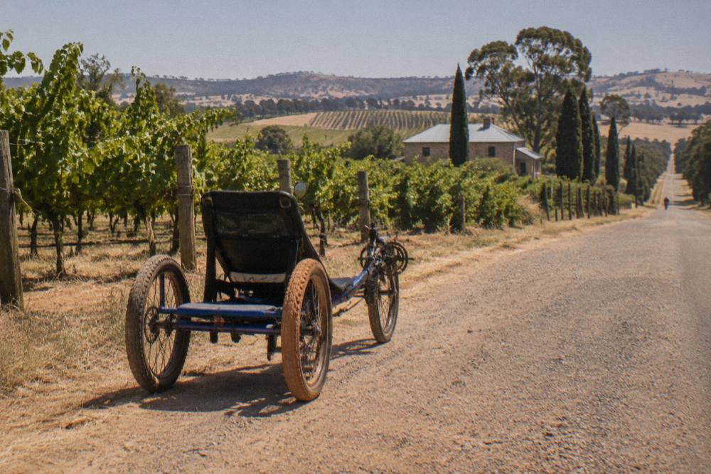 A three-wheeled trike parked on a country road between Tanunda vineyards