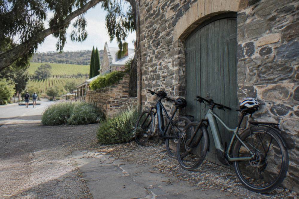 Electric bicycles parked outside a stone cellar door in Angaston