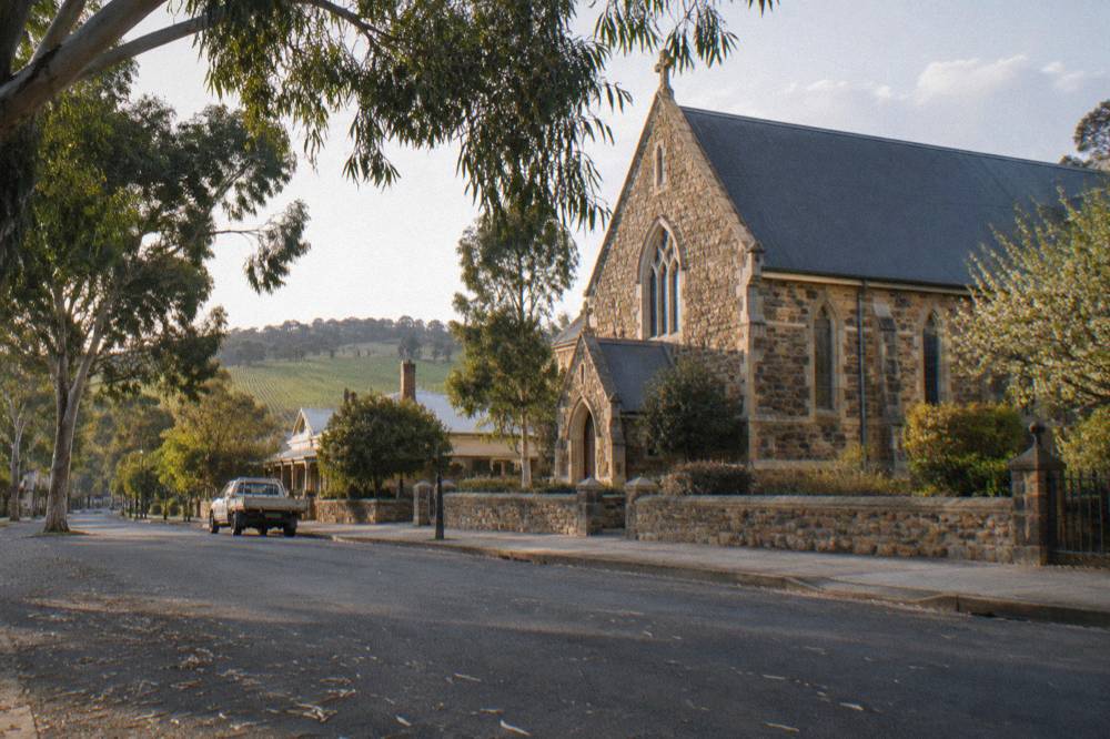 A historic stone church and heritage shopfronts along a quiet country main street with no people
