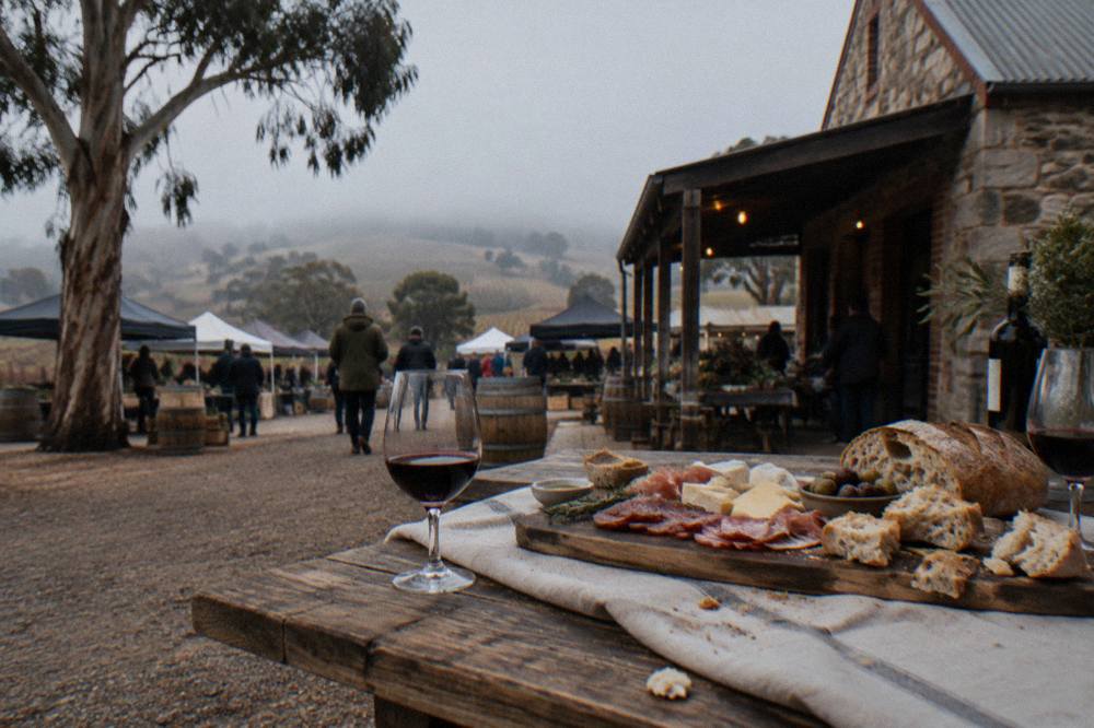 A regional platter of meats, cheese and bread on a winery table with glasses of red wine