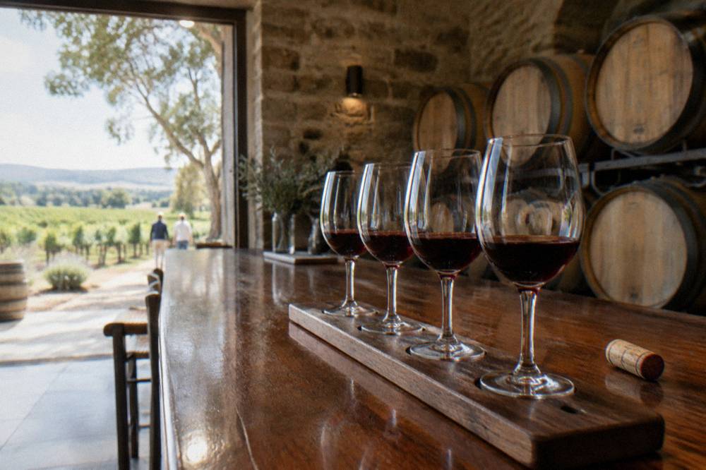 A tasting flight of red wines lined up on a timber cellar door bar