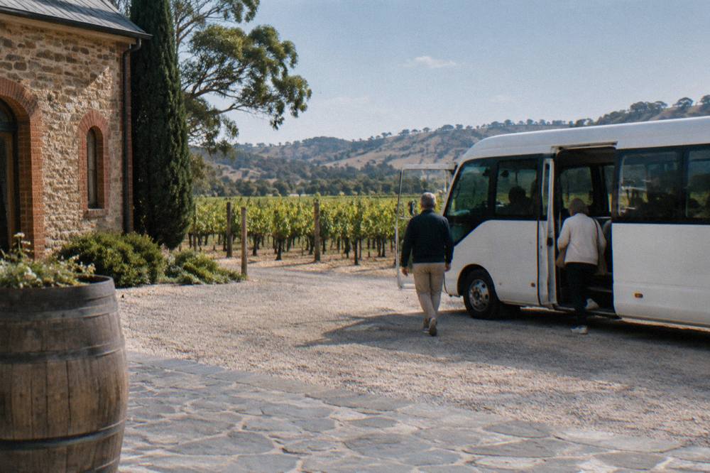 The hop-on hop-off bus parked near a vineyard with passengers stepping off.