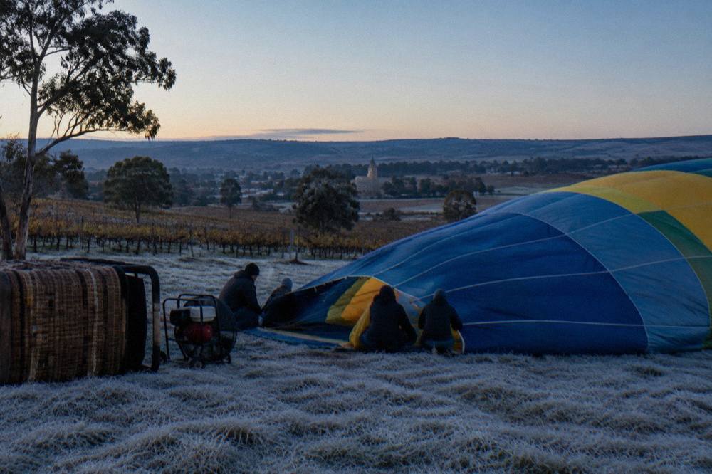 A hot air balloon envelope being inflated on a frosty paddock at first light
