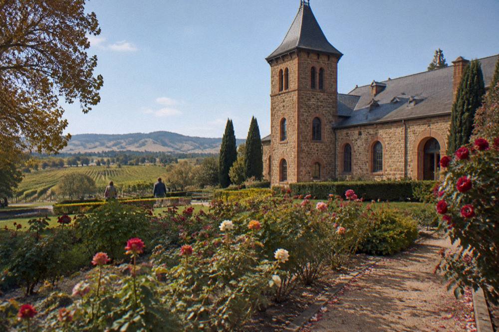 Historic sandstone winery facade with rose garden and vineyard beyond