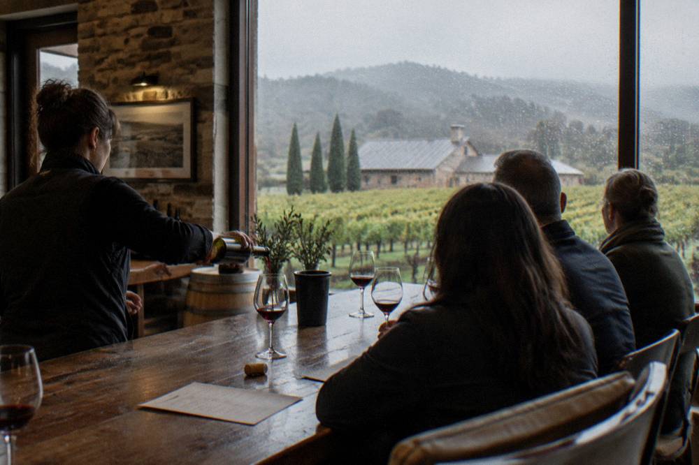A small group tasting wine together at a cellar door bar with a guide pouring