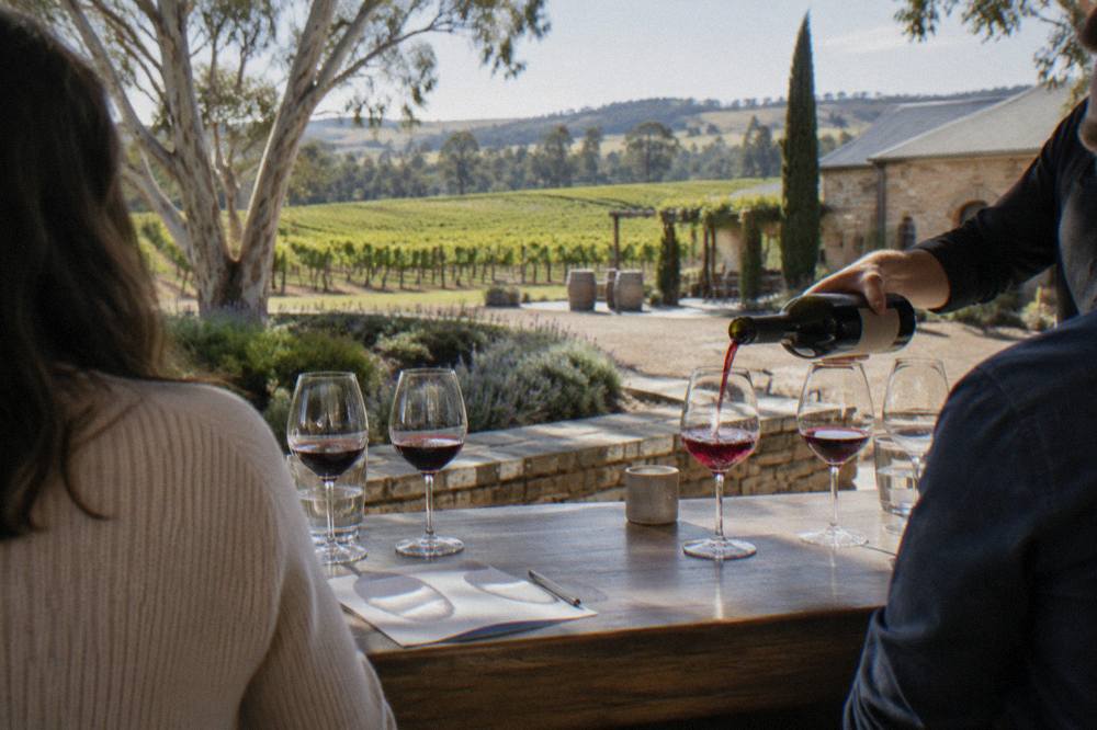 A small group tasting red wine at a wooden cellar door counter