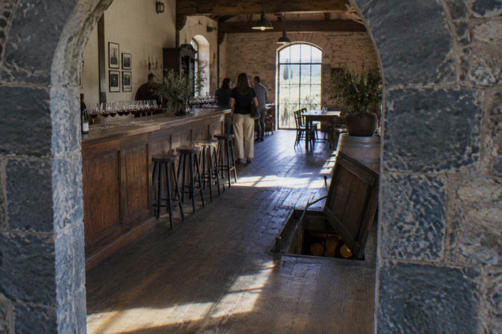 A cellar door tasting room with glasses of red wine lined along a timber bar