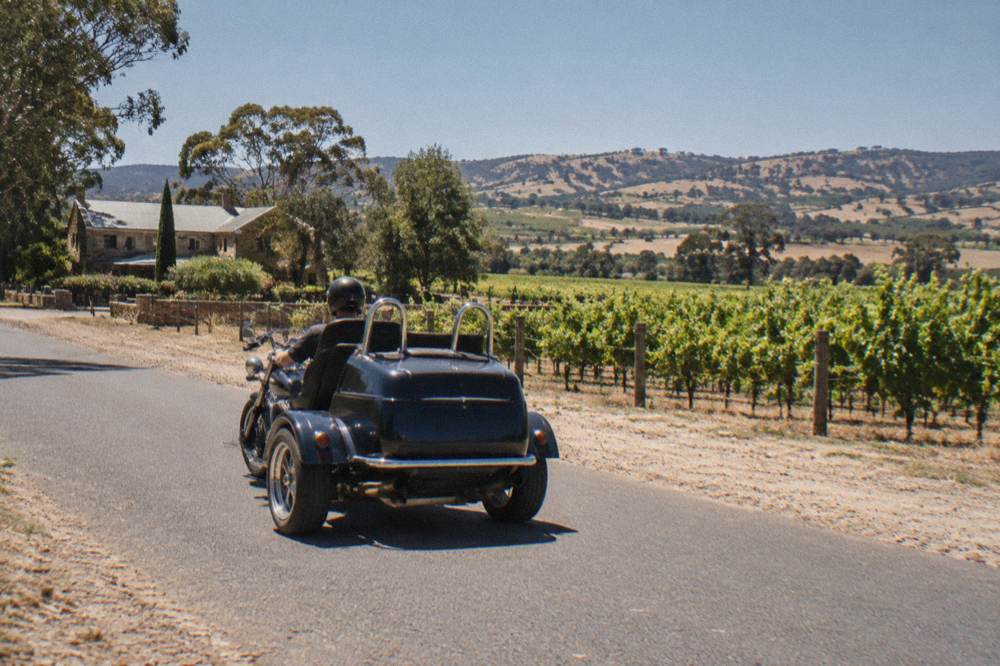 A three-wheeled trike parked on a country road between vineyards