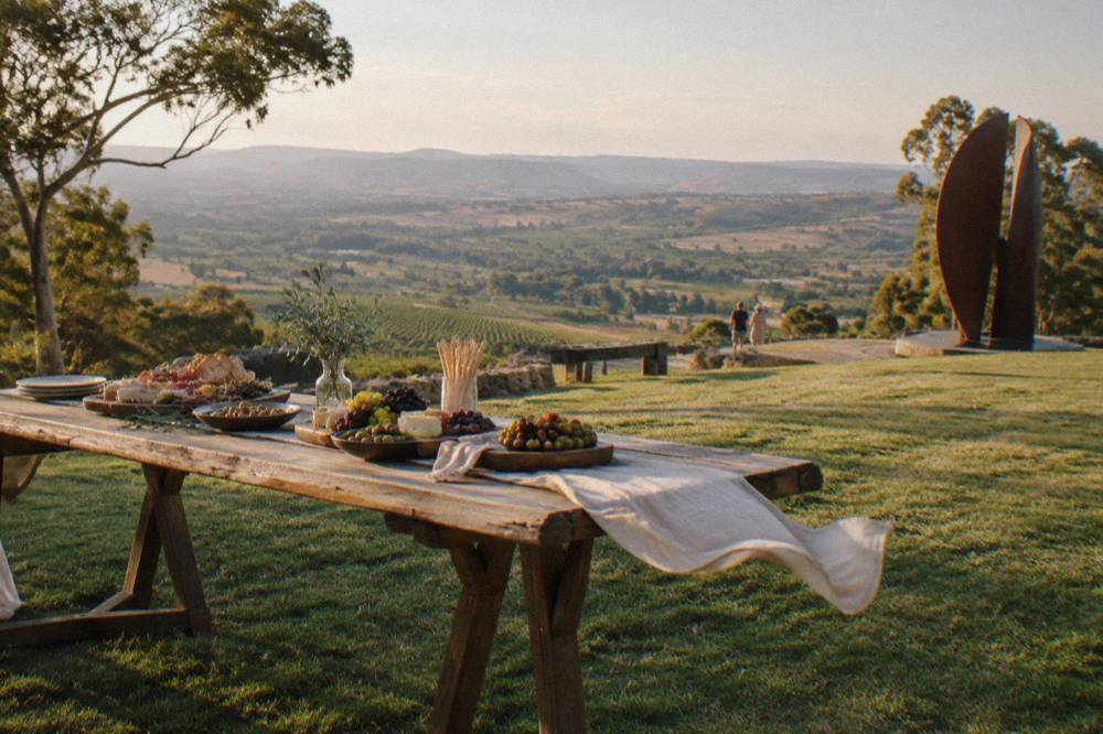 Long timber table set for lunch with platters of regional produce