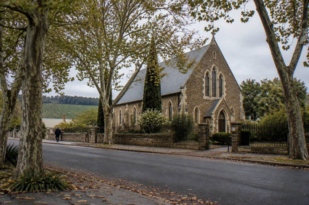 Historic stone church surrounded by plane trees in a Barossa village